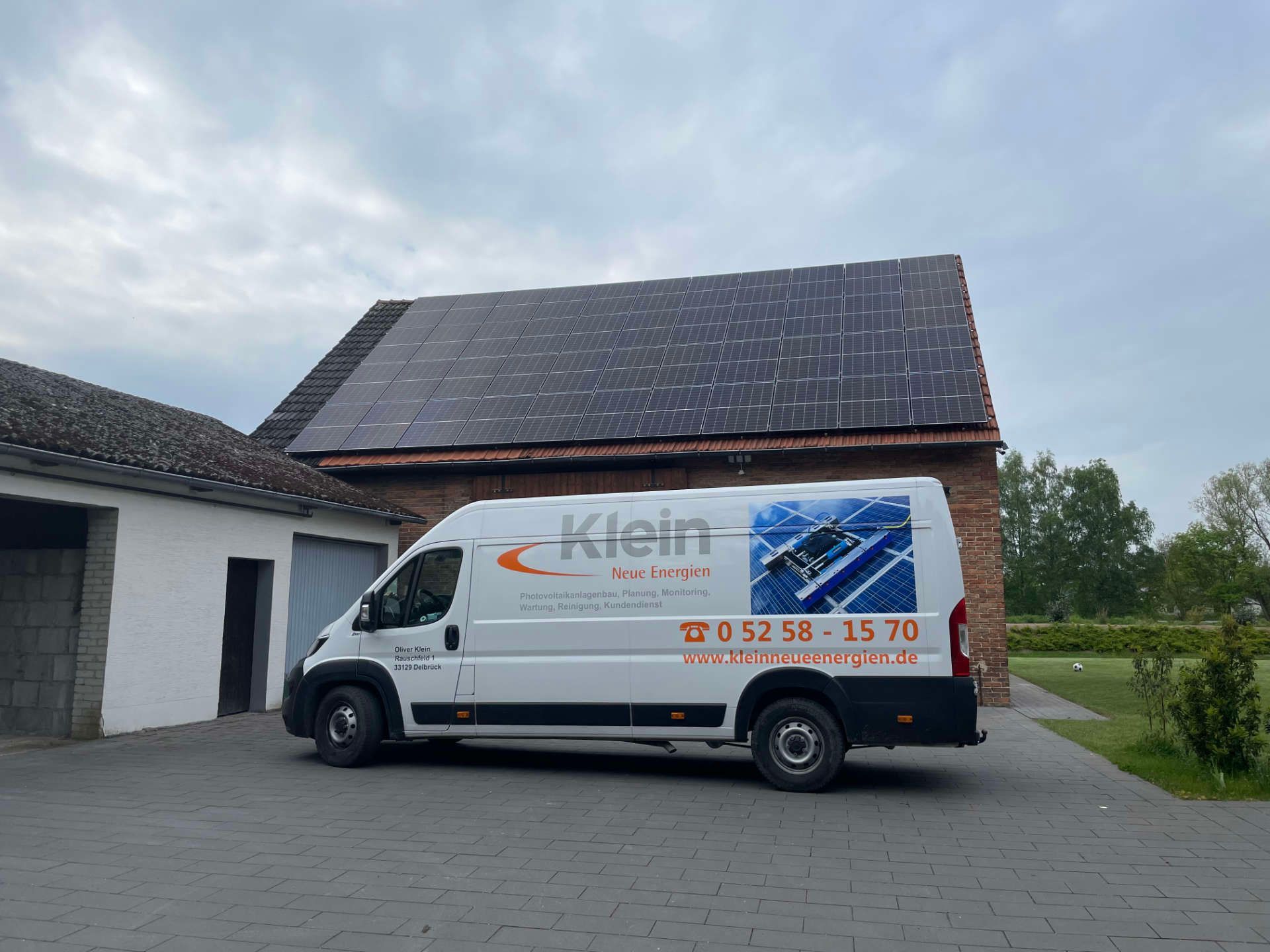 KNE Lieferwagen parkt vor einem Gebäude mit Solarzellen auf dem Dach.