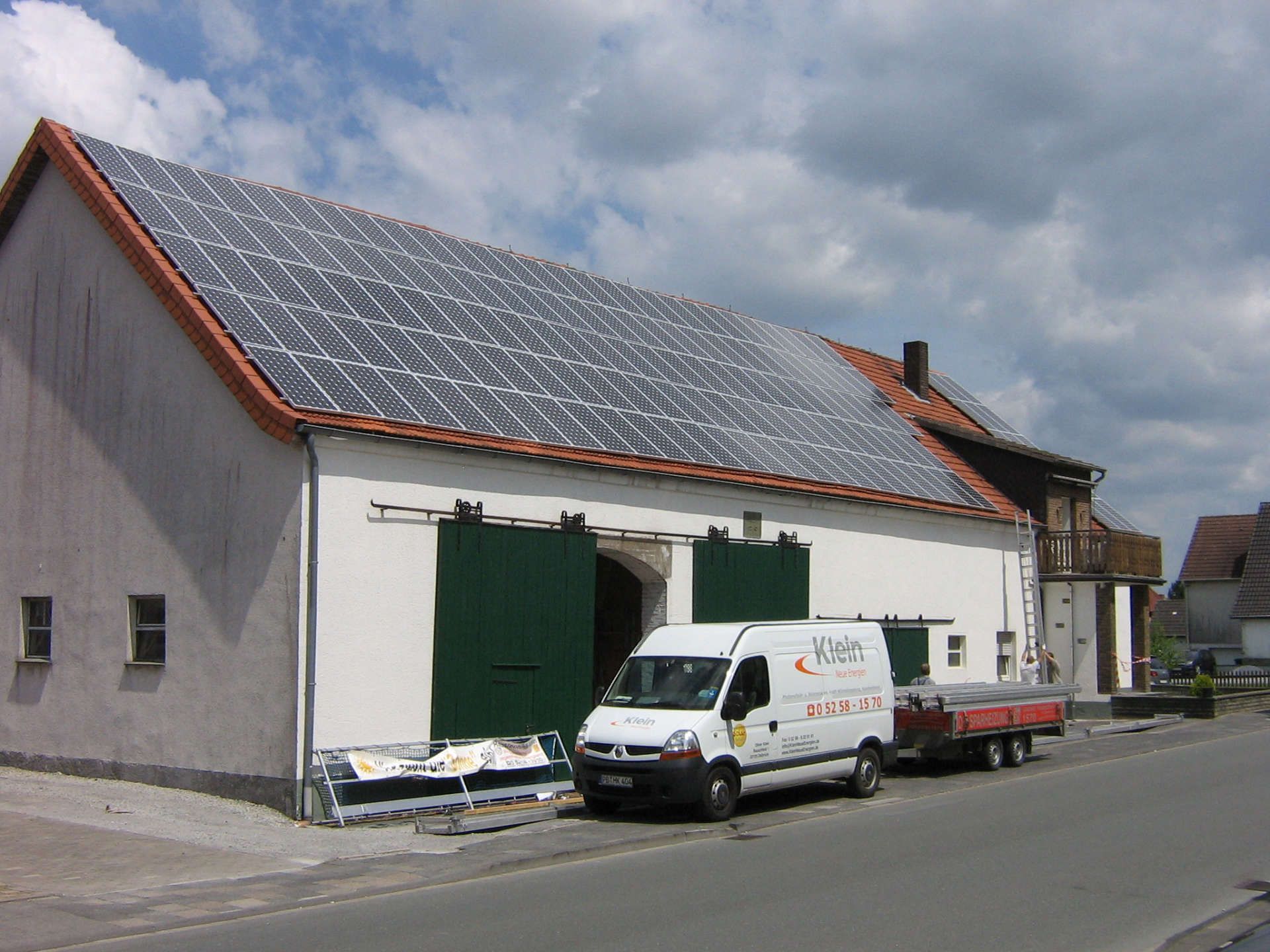 KNE Lieferwagen steht vor einem Gebäude mit Sonnenkollektoren auf dem Dach