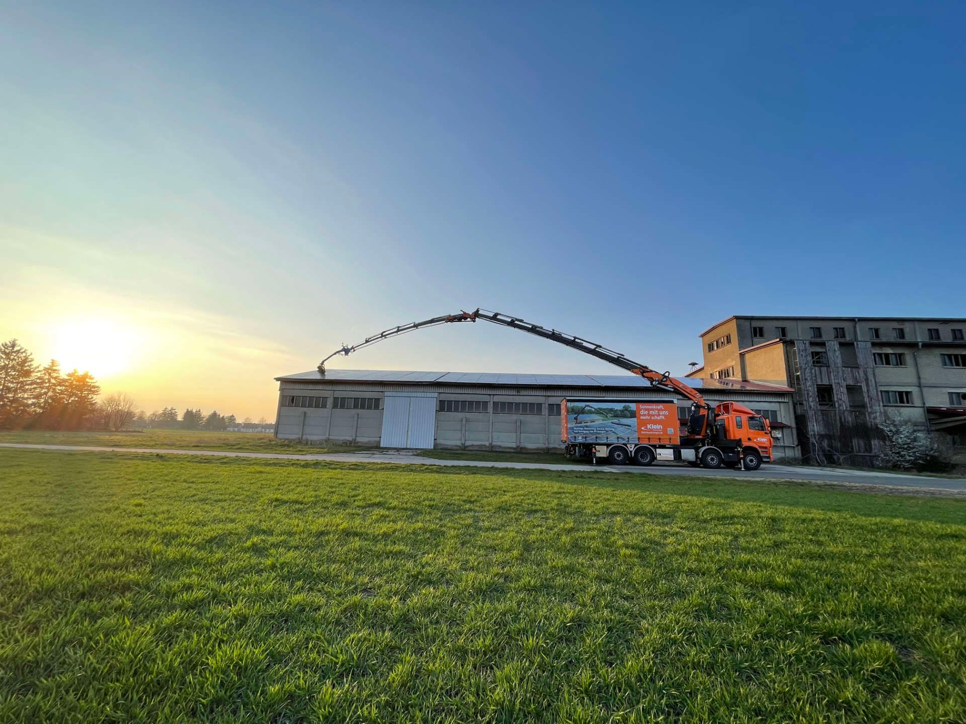 Vor einem Gebäude parkt ein LKW mit einem daran befestigten Kran.