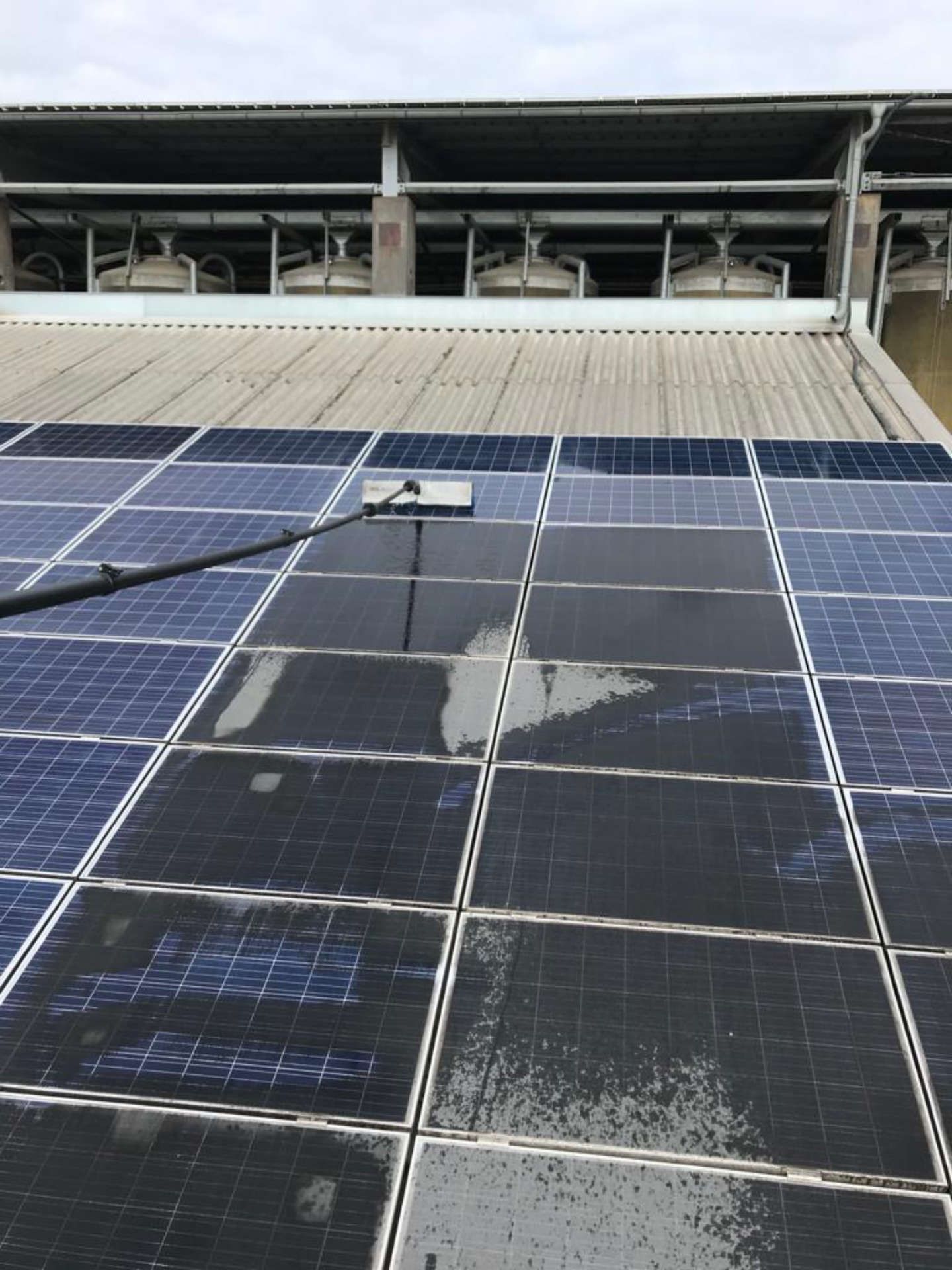 Auf dem Dach eines Gebäudes wird eine Reihe von Solarmodulen gereinigt.