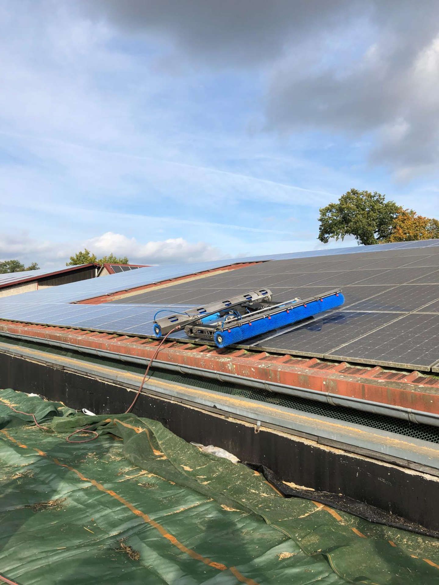 Auf einem Dach mit Solarmodulen steht ein blaues Werkzeug.