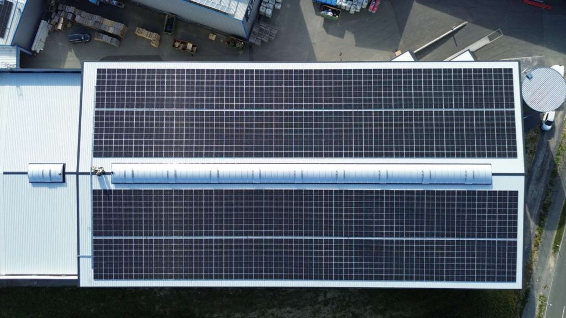 Eine Luftaufnahme eines Gebäudes mit Solarmodulen auf dem Dach.