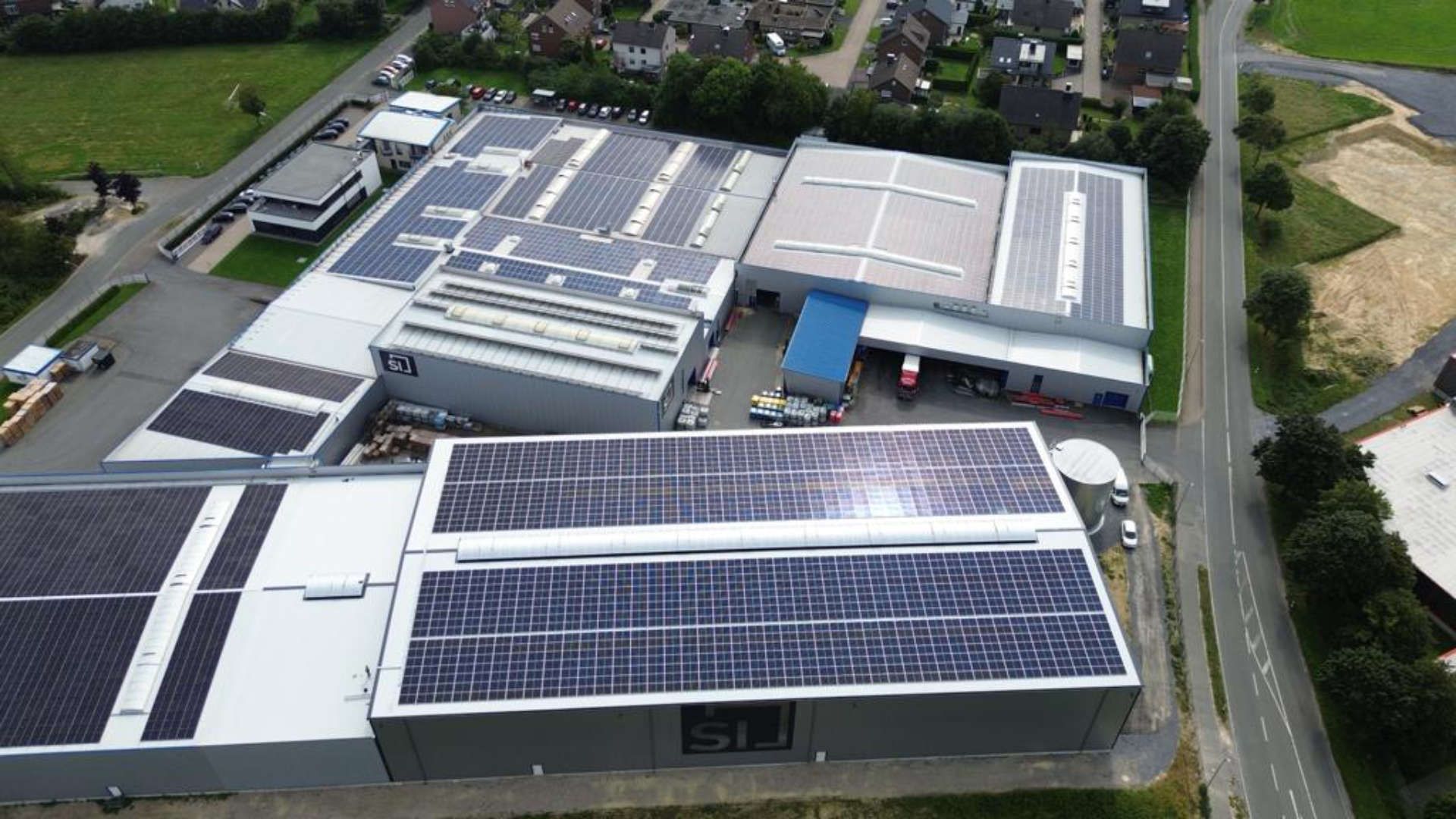 Eine Luftaufnahme eines großen Gebäudes mit Solarmodulen auf dem Dach.