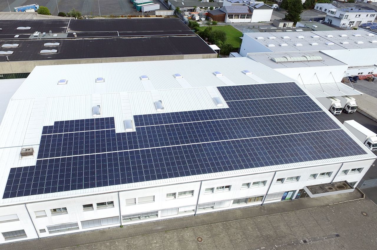 Eine Luftaufnahme eines großen Gebäudes mit Solarmodulen auf dem Dach.