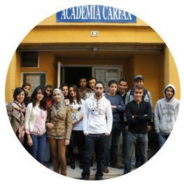 Un grupo de personas de pie frente a un edificio que tiene la palabra academia escrita en él.