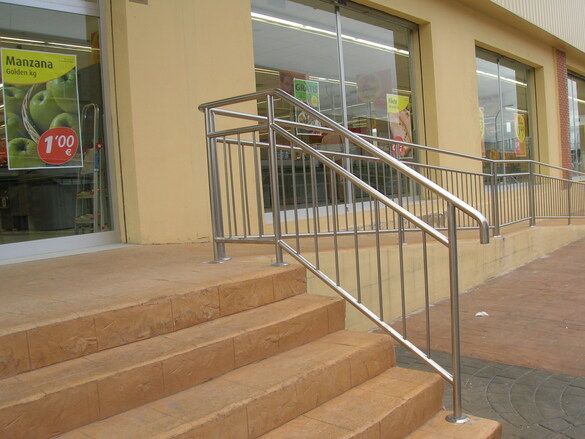 Escaleras que conducen a una tienda con barandilla de acero inoxidable.