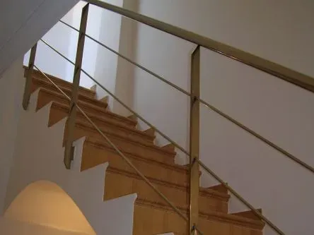 Una escalera de madera con barandilla de metal que sube al segundo piso.