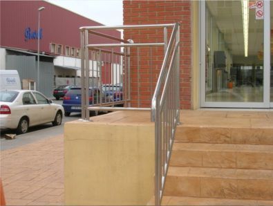 Una escalera con barandilla de acero inoxidable que conduce a un edificio.