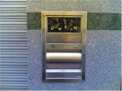 Un buzón de acero inoxidable con una cruz verde.