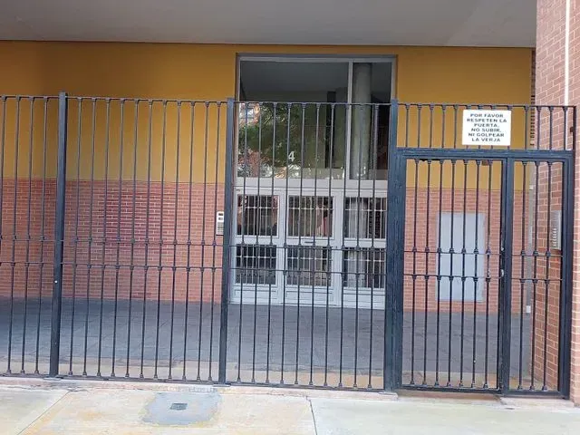 Un edificio de ladrillo con una valla de hierro forjado a su alrededor.