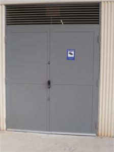 Una puerta de garaje gris con un cartel azul.