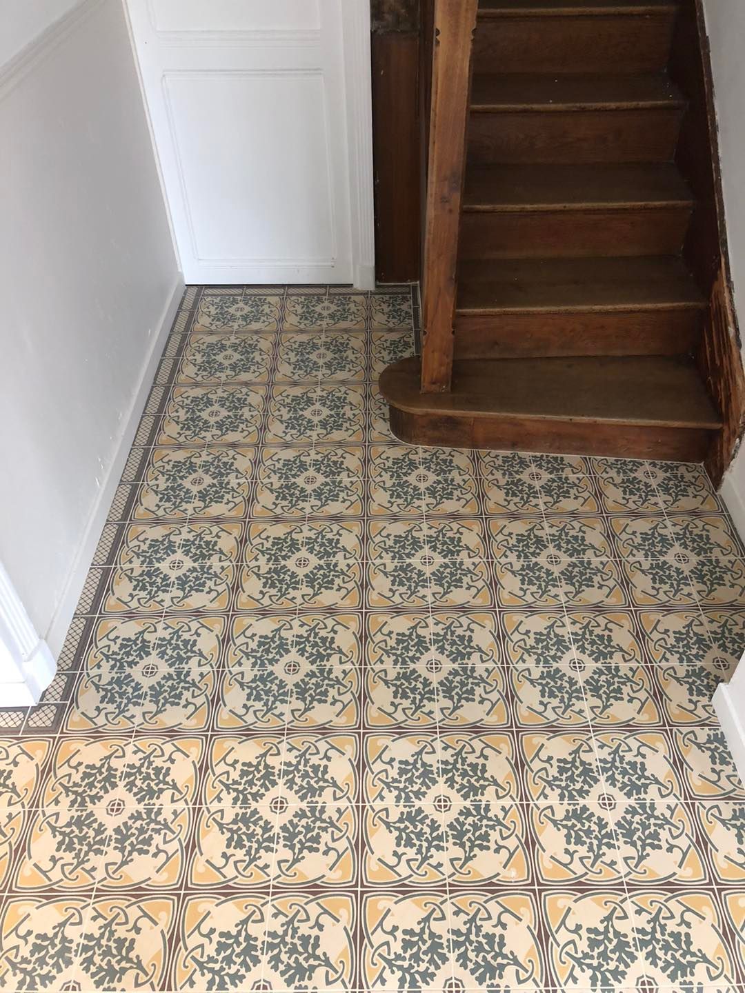 Une entrée de maison carrelée avec un escalier en bois.