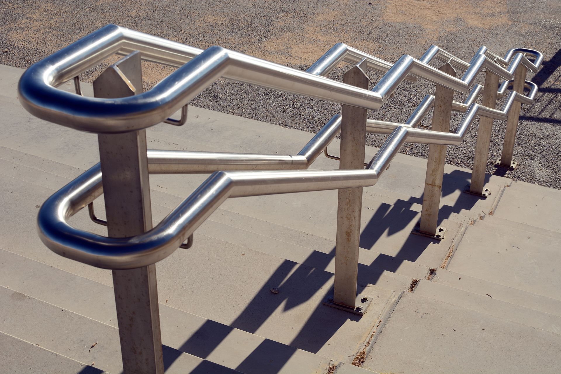 Rambardes métalliques brillantes au design en zigzag unique sur des escaliers en béton.