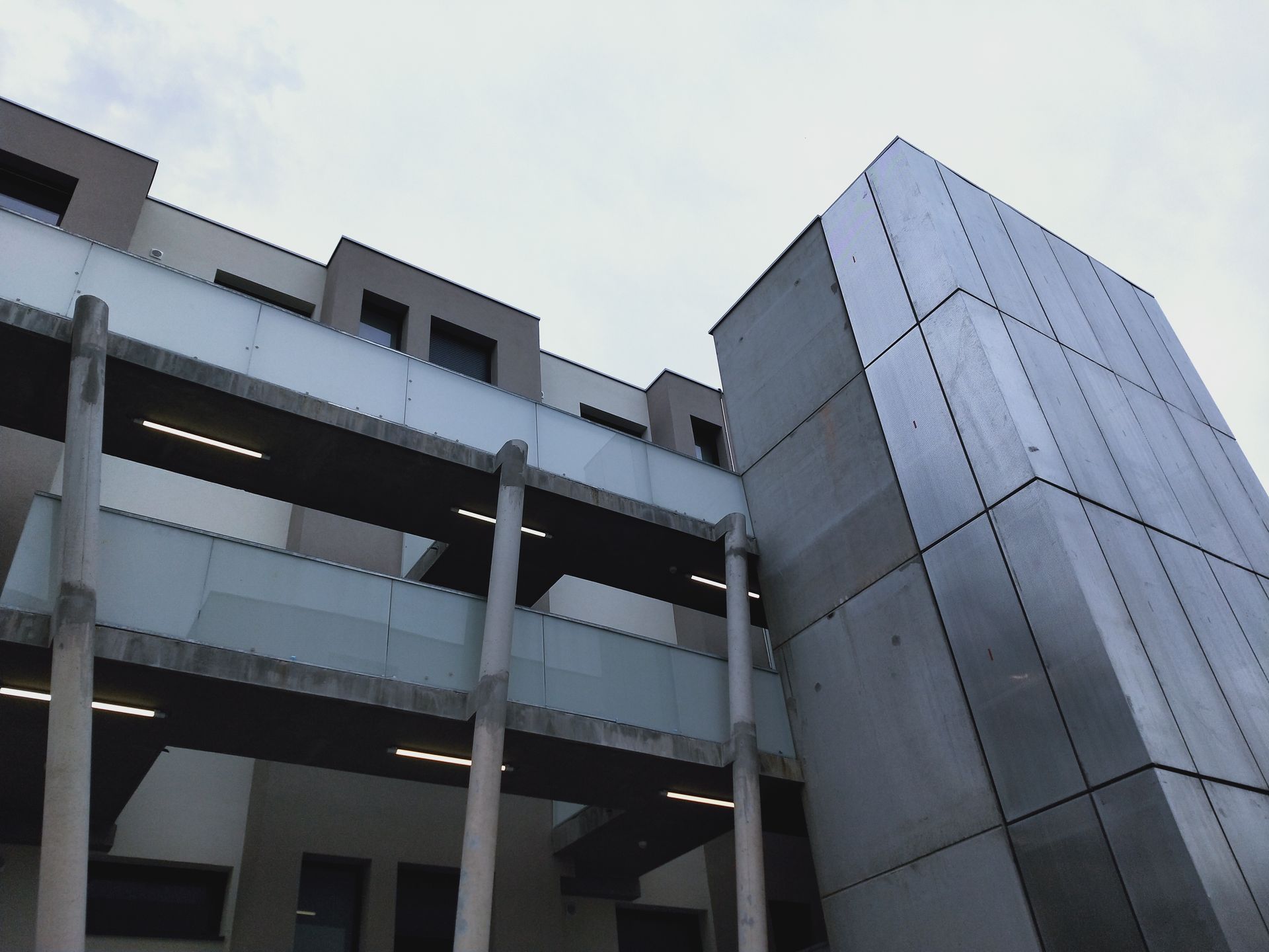 Deux passerelles métalliques circulaires surélevées relient deux bâtiments en béton en construction.