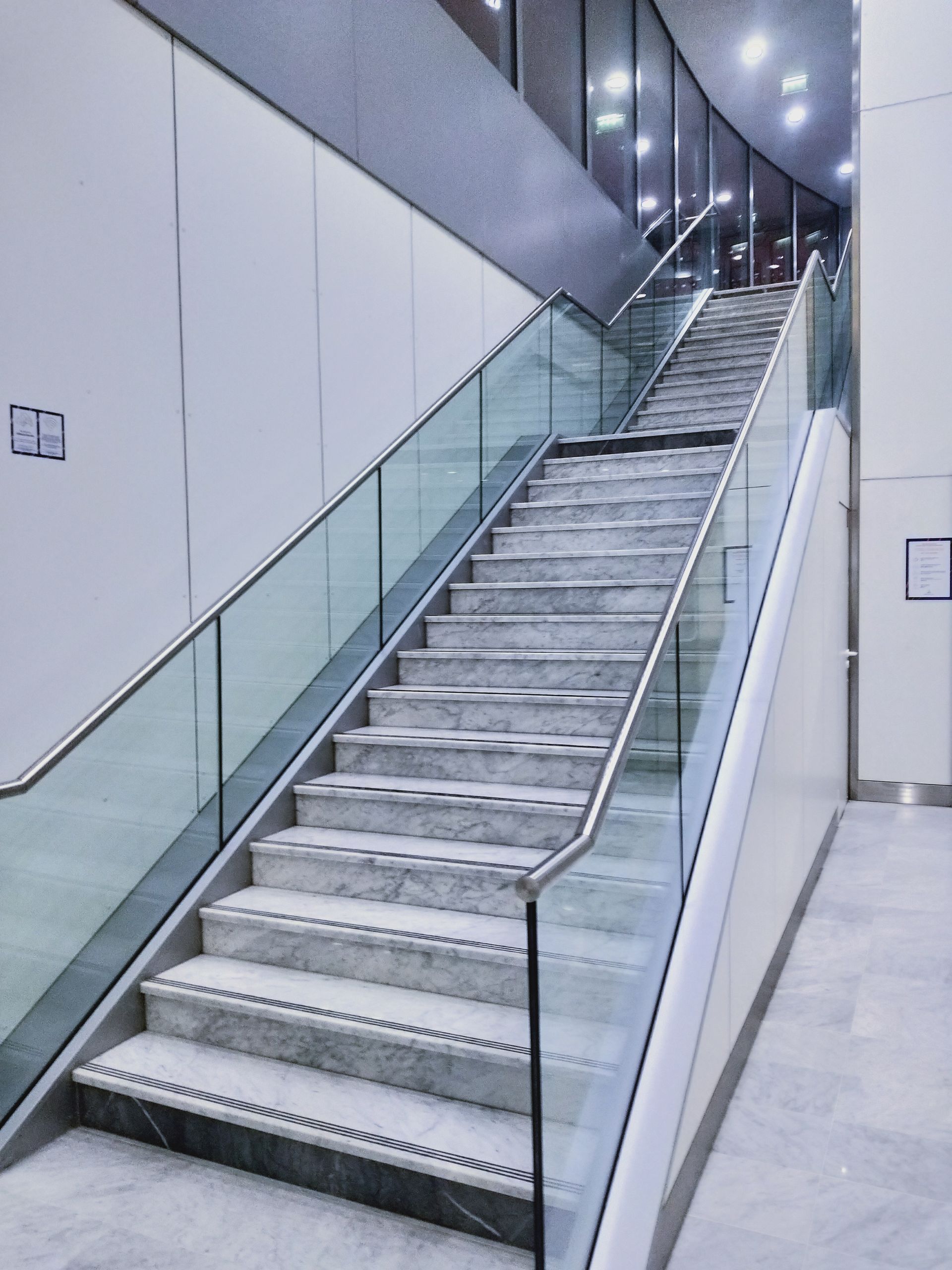 Immeuble de plusieurs étages en construction ; façade en béton et en verre avec poutres verticales noires. Grue visible.