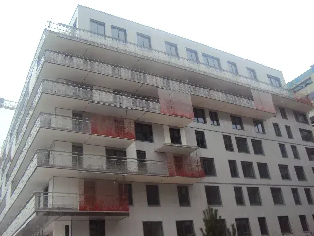 Rambarde en métal noir sur un balcon en béton, se détachant sur un ciel nuageux.