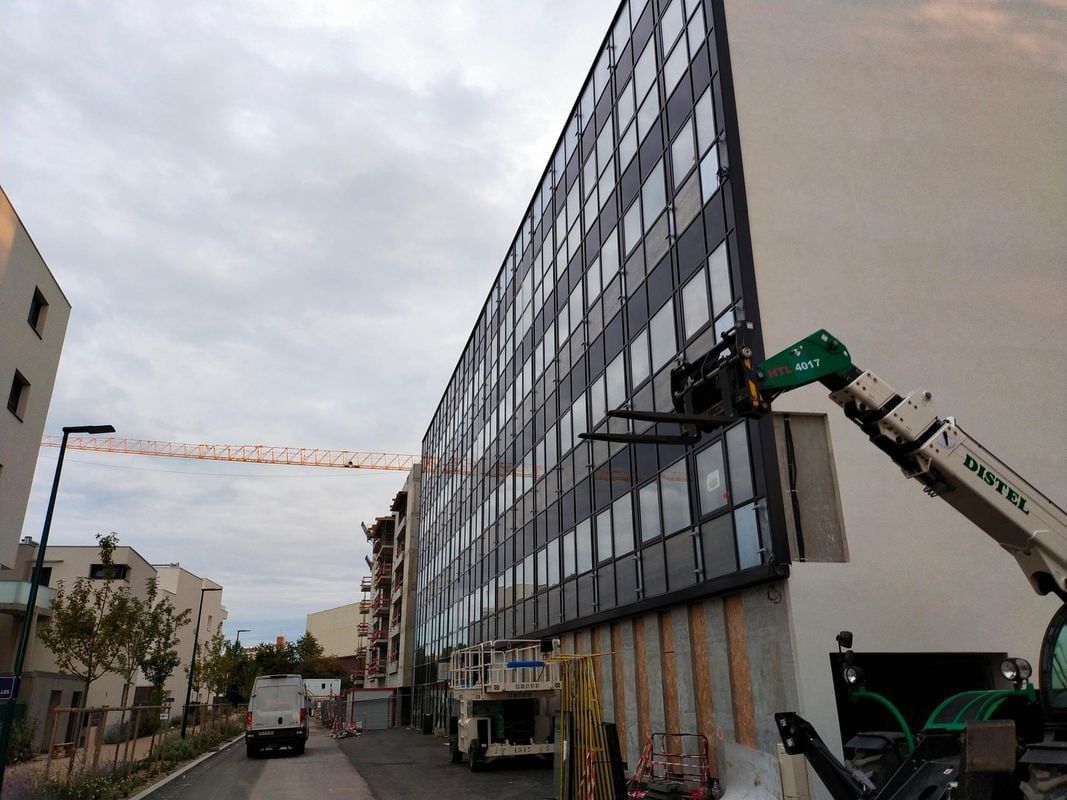Façade de gratte-ciel en verre offrant une vue imprenable sur la ville par une journée ensoleillée.