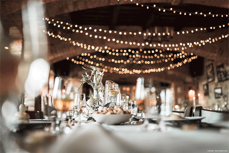 Ein für einen Hochzeitsempfang gedeckter Tisch mit einer Schüssel Essen und Gläsern Wein.
