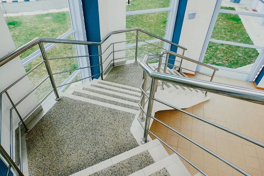 Una escalera de caracol con barandilla de acero inoxidable en un edificio.