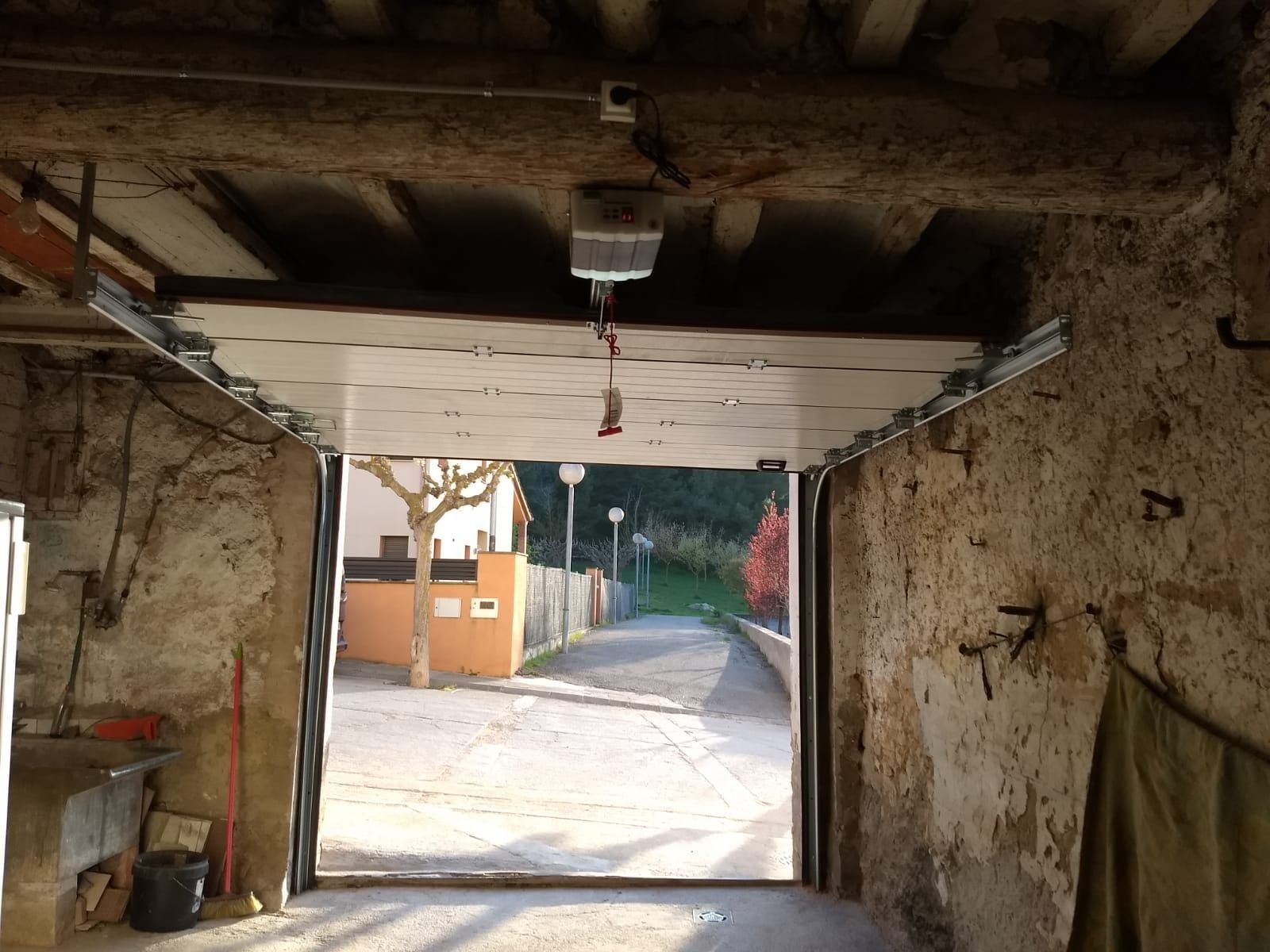 Una puerta de garaje está abierta a un camino de entrada que conduce a una casa.