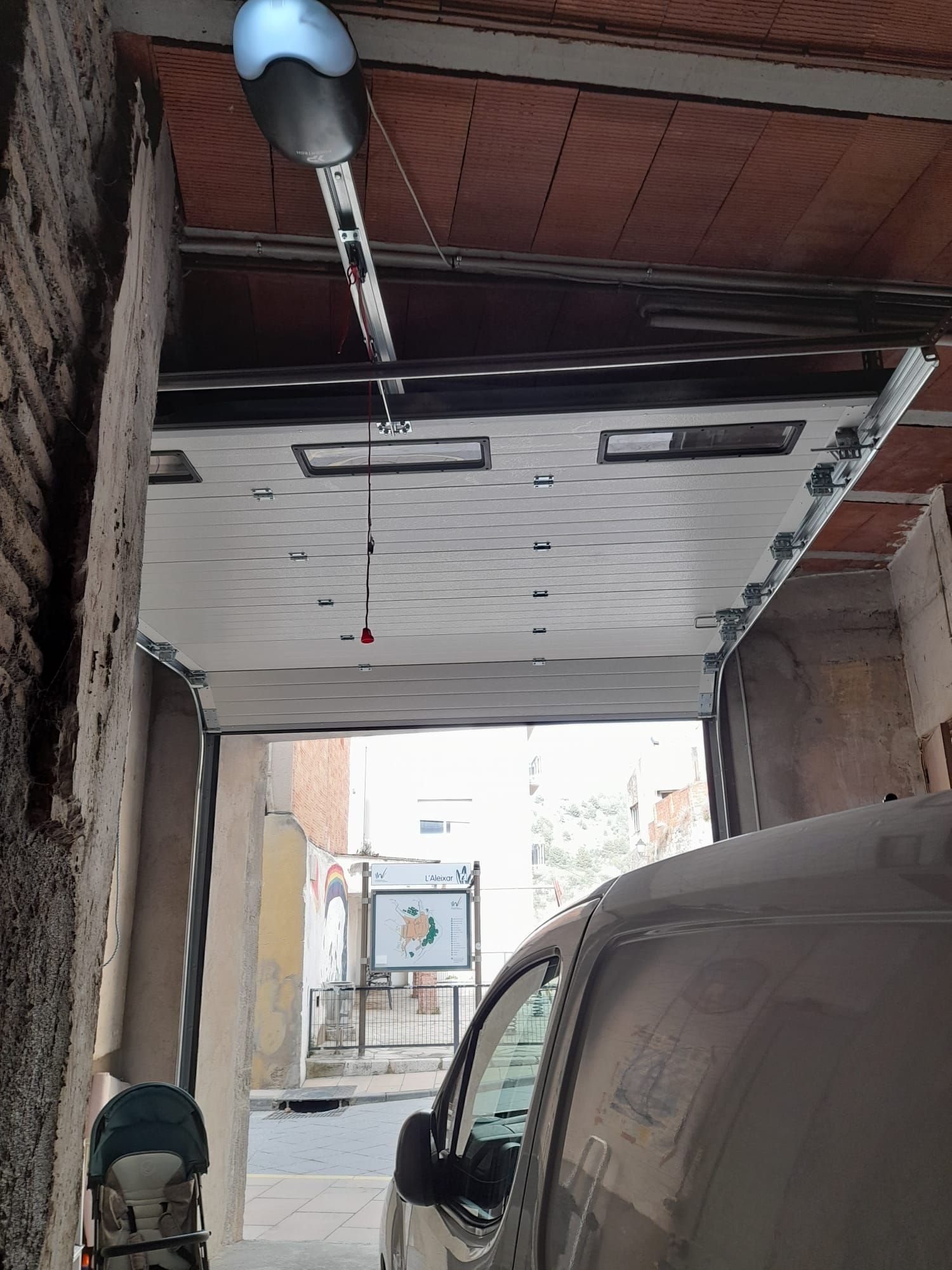 Un coche está aparcado en un garaje con la puerta abierta.