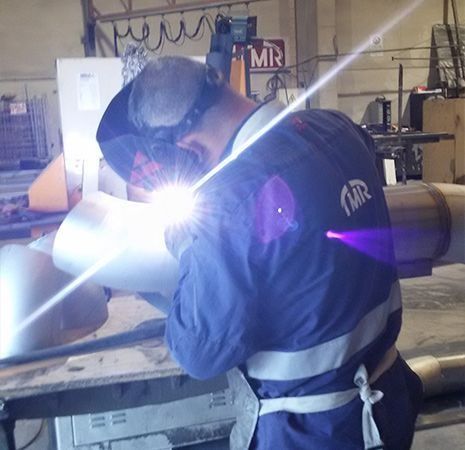 Un hombre está soldando una tubería con un cartel que dice 