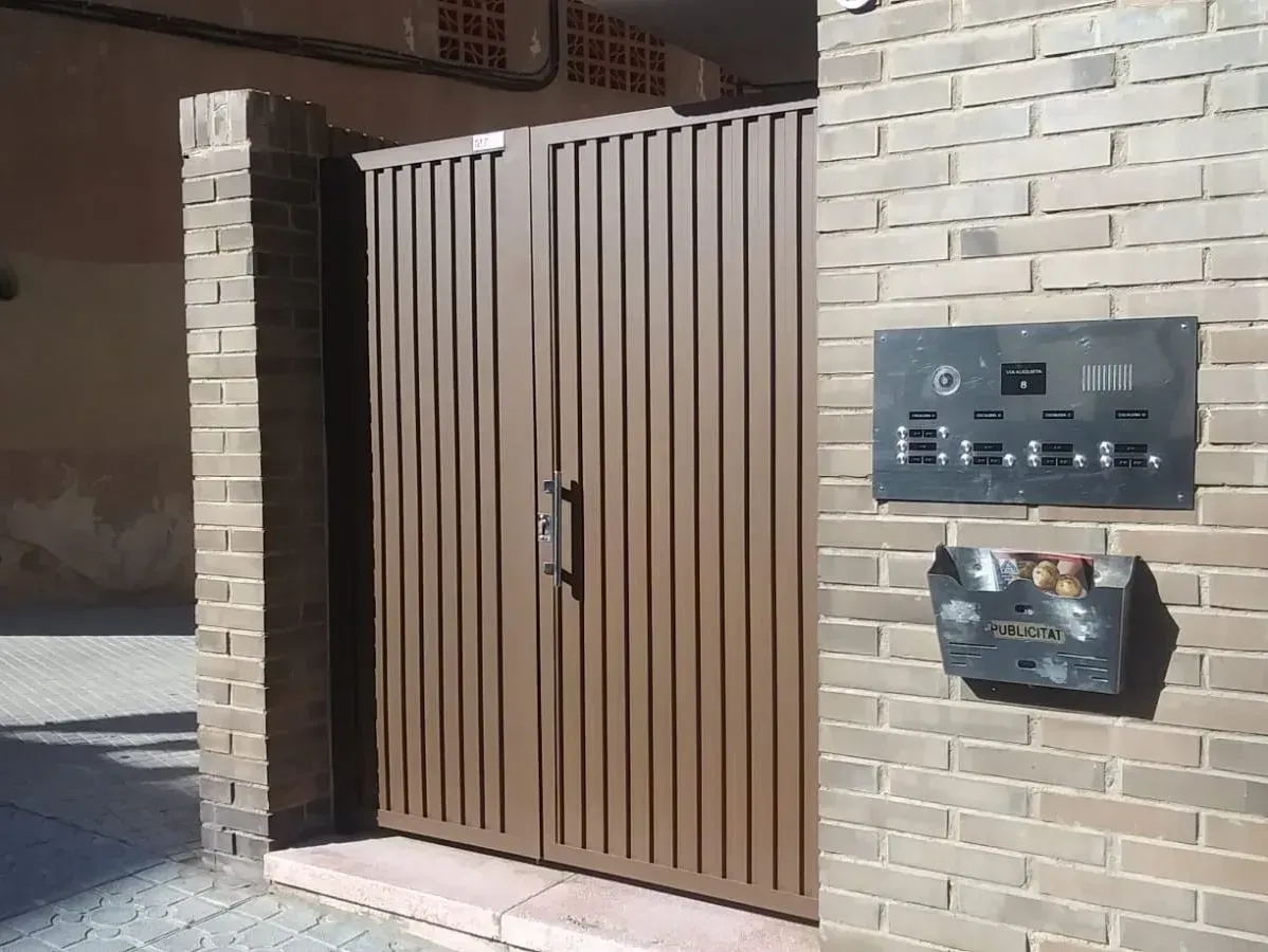 Una pared de ladrillos con una puerta y un buzón encima.