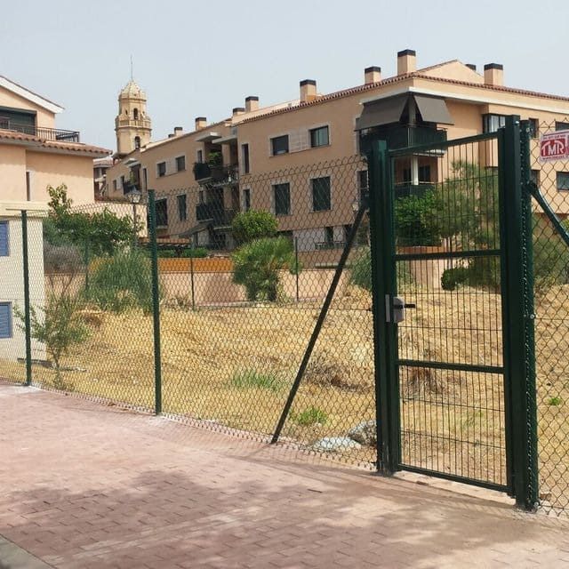 Una valla de alambre con una puerta y un edificio al fondo.