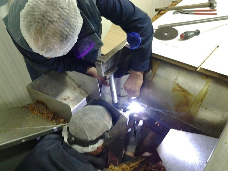 Un hombre que lleva una máscara de soldar está trabajando en una máquina.