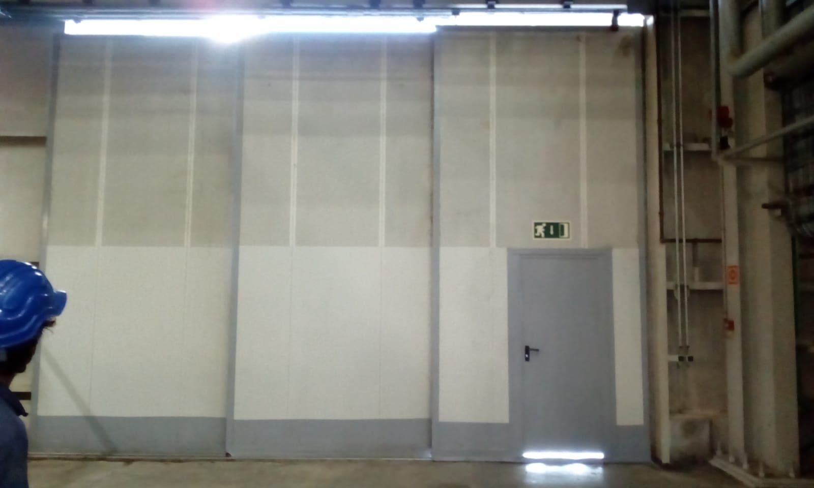 Un hombre que lleva un casco azul está de pie en una habitación vacía.