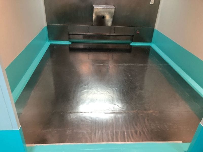 Una habitación con suelo de acero inoxidable y paredes azules.