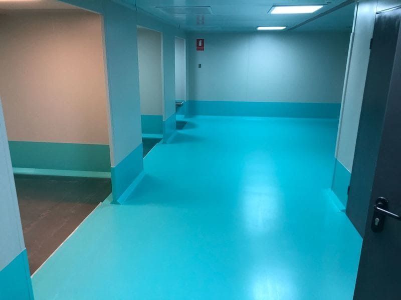 Un pasillo con suelo azul y paredes blancas.