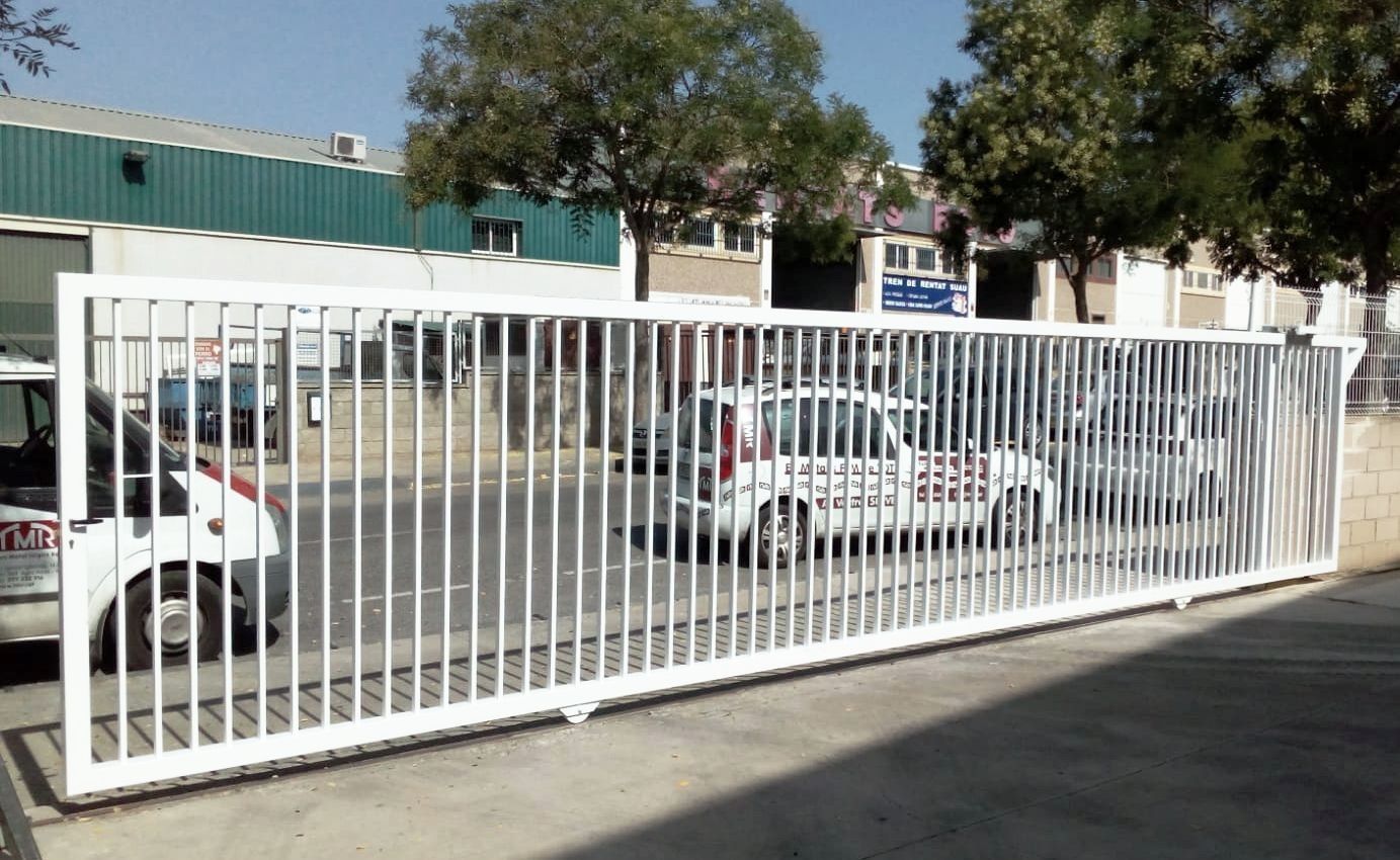 Un coche blanco está aparcado detrás de una valla blanca.