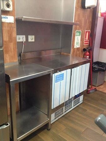 Una cocina con encimera de acero inoxidable y refrigerador.