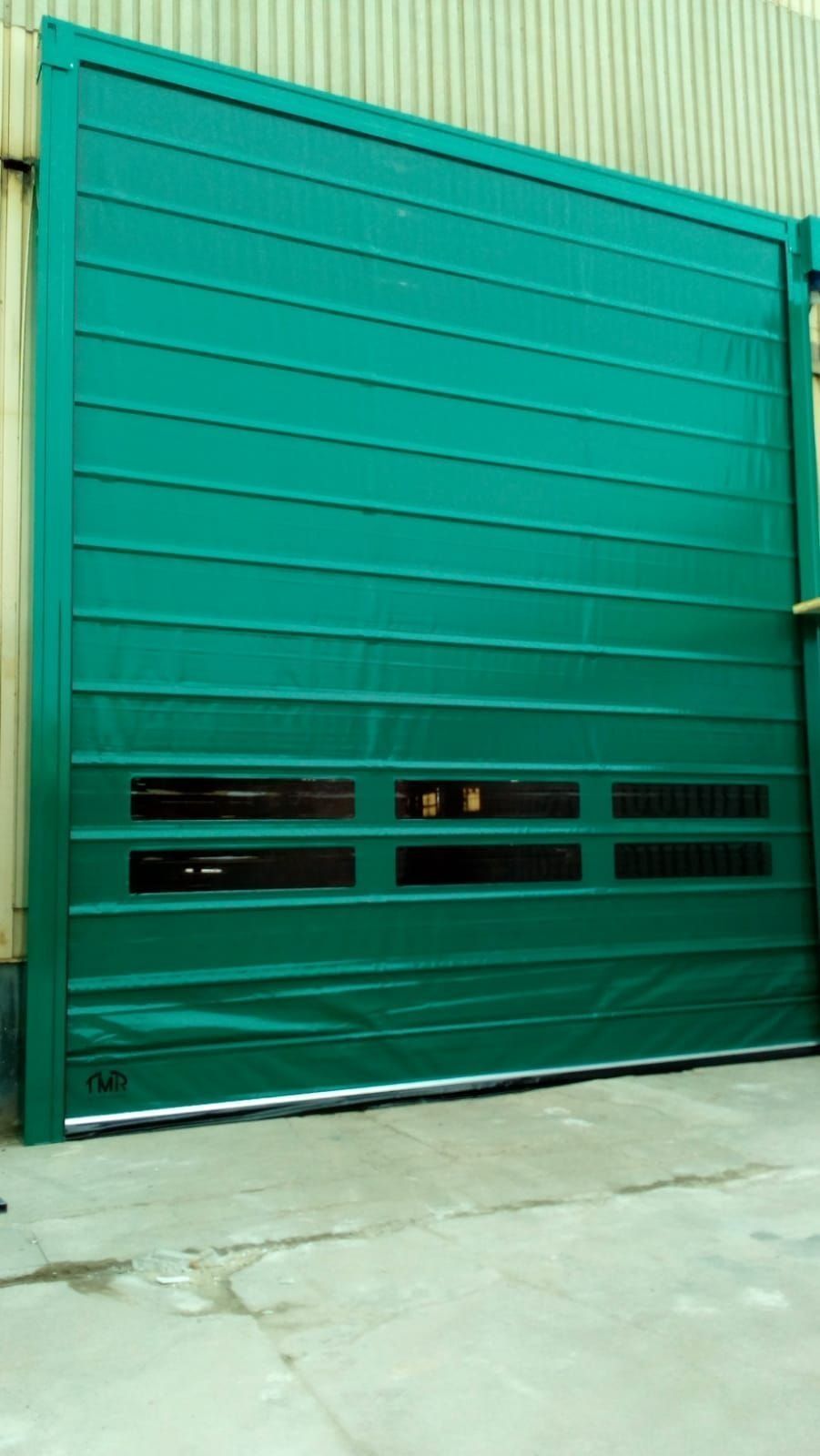 Una gran puerta de garaje verde se encuentra frente a un edificio.