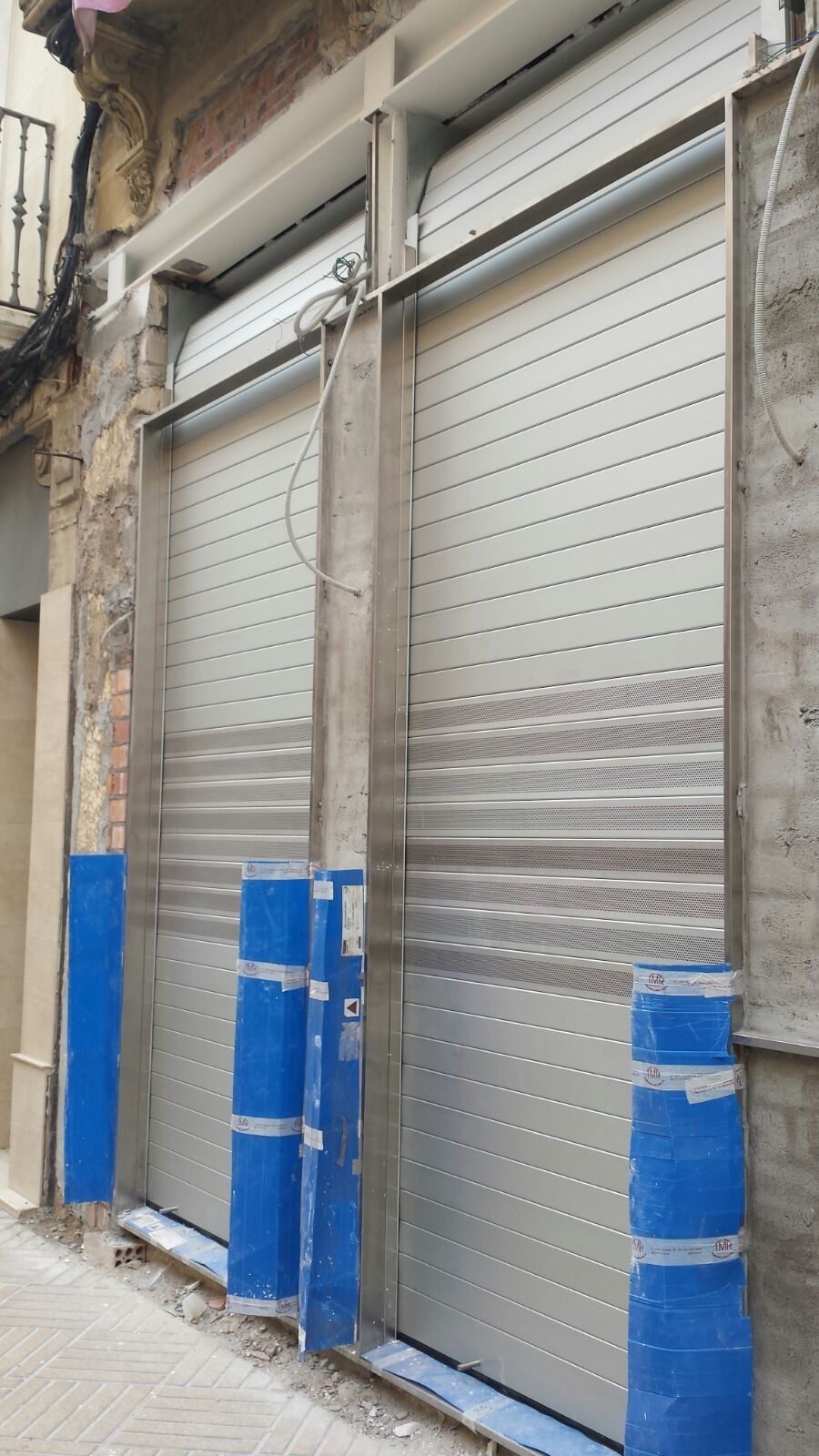 Un edificio con una hilera de persianas enrollables a un costado.