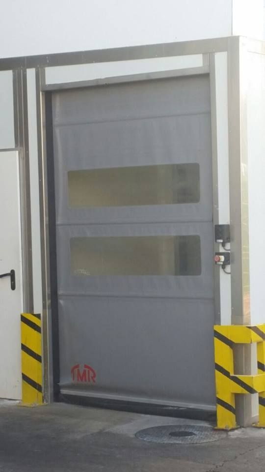 Una puerta gris con una barrera amarilla delante de ella.