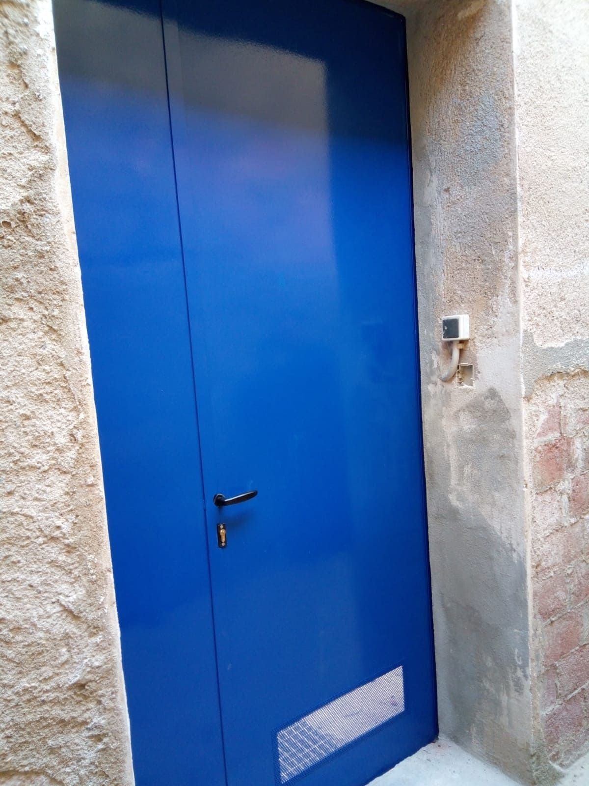 Una puerta azul está sentada al costado de un edificio.