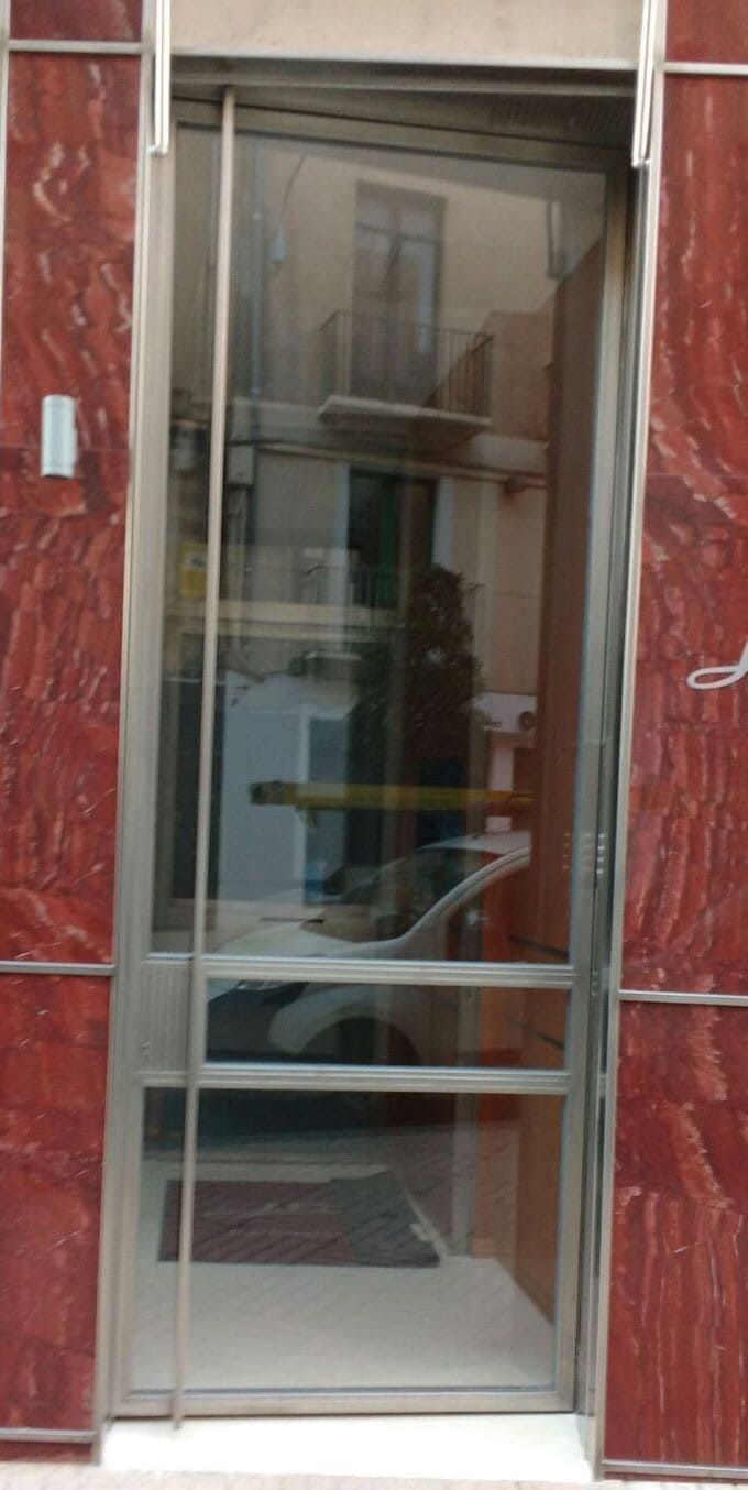 Una puerta de vidrio con marco de acero inoxidable está en un edificio.