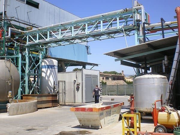 Un hombre está parado frente a un gran edificio industrial.