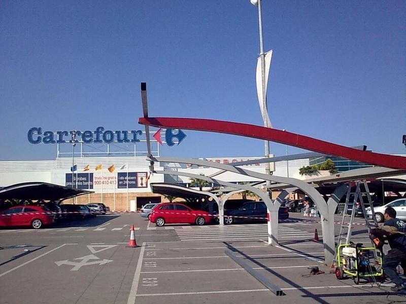 Un estacionamiento con autos estacionados frente a una tienda Carrefour
