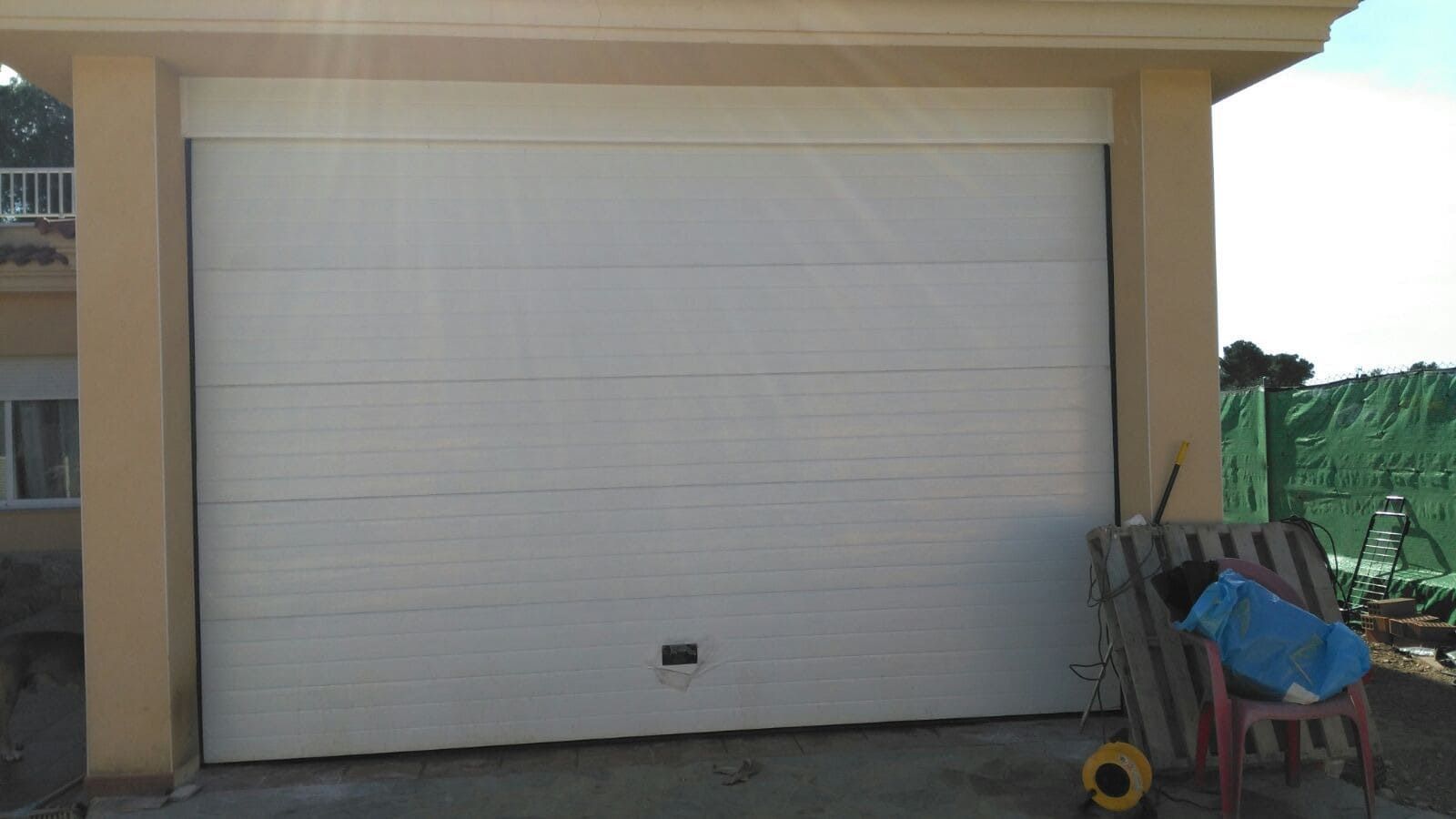 Una puerta de garaje blanca está abierta delante de una casa.