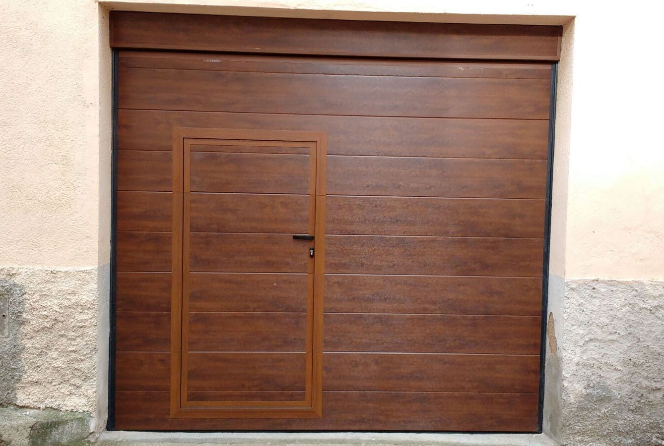 Una puerta de garaje marrón con una pequeña puerta en ella