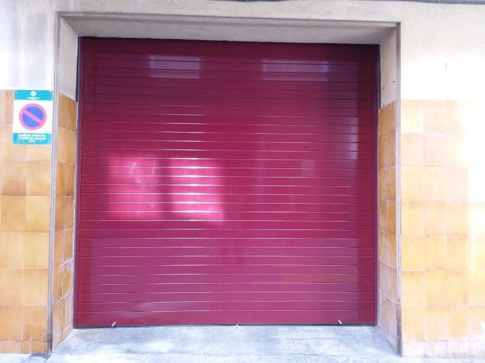 Una puerta de garaje roja con una señal de no estacionar detrás.