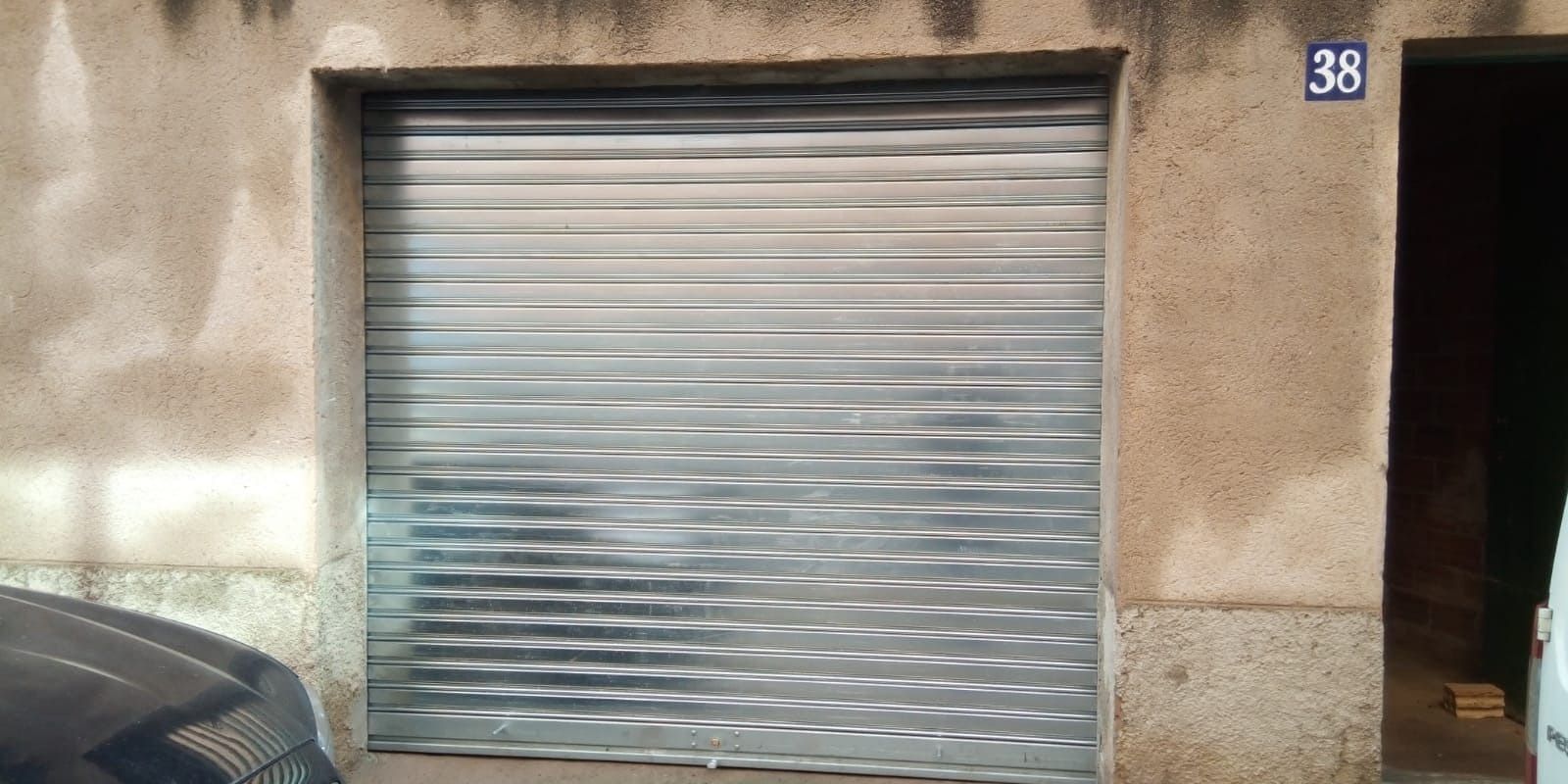 Un coche está aparcado delante de un edificio con puerta de garaje.