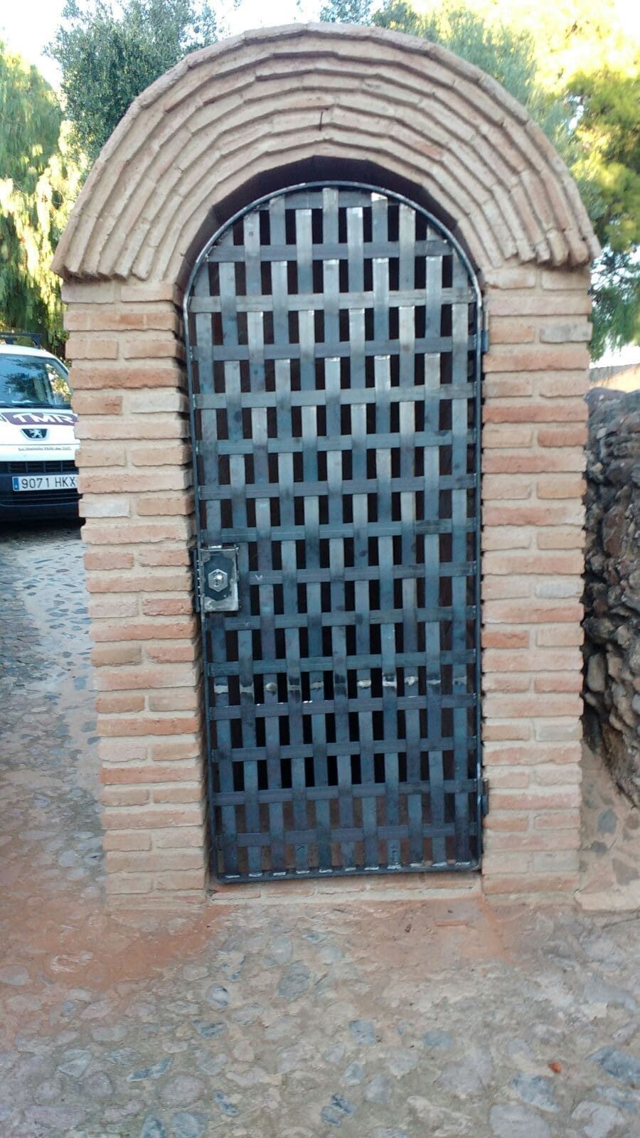 Un edificio de ladrillo con una puerta de metal y un coche aparcado delante.