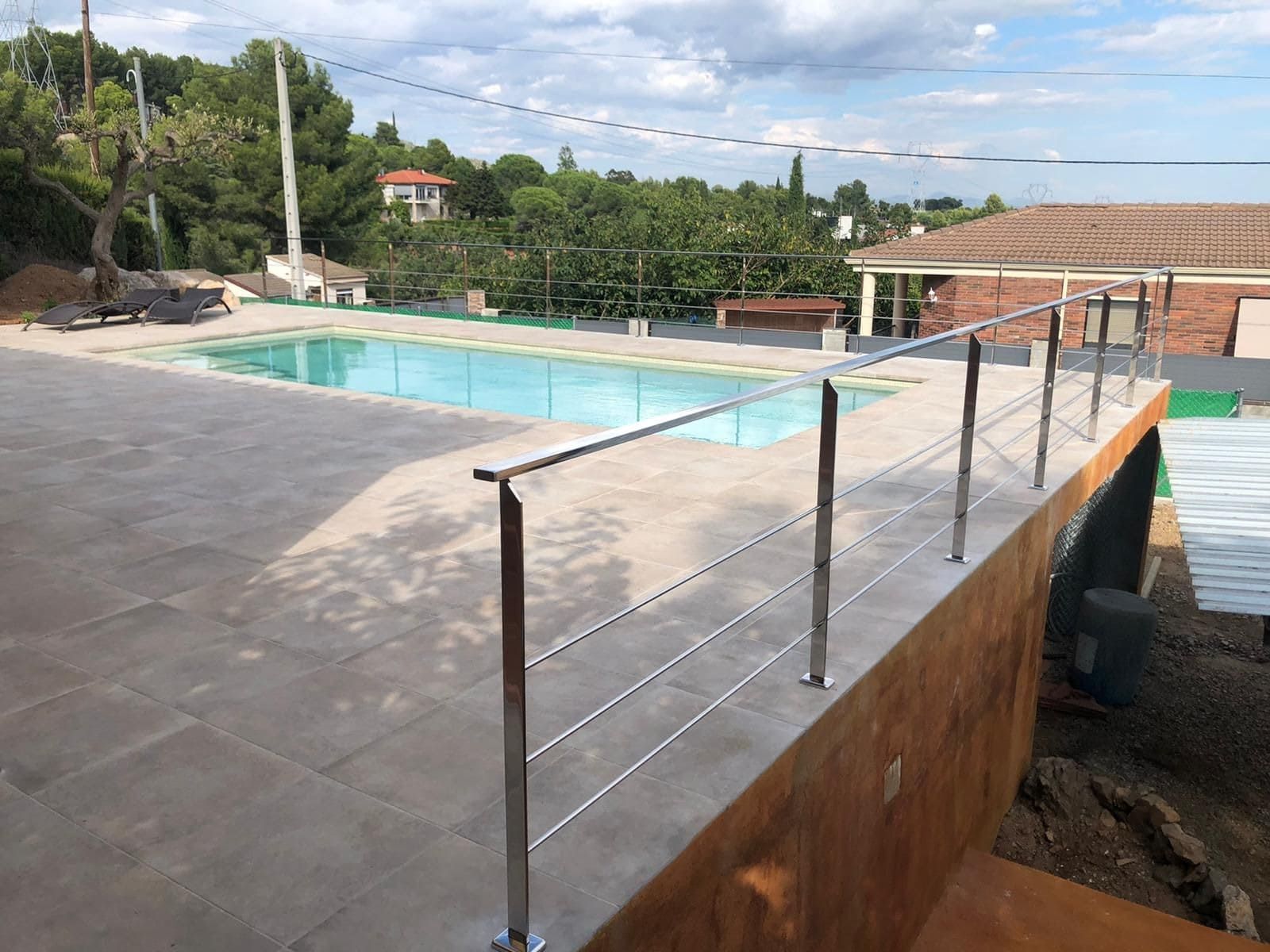 Una piscina con una barandilla de acero inoxidable que la rodea.