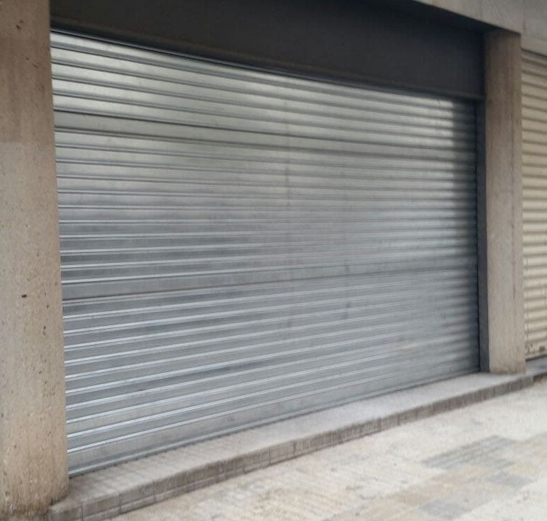 Una puerta de garaje gris está cerrada en un edificio.