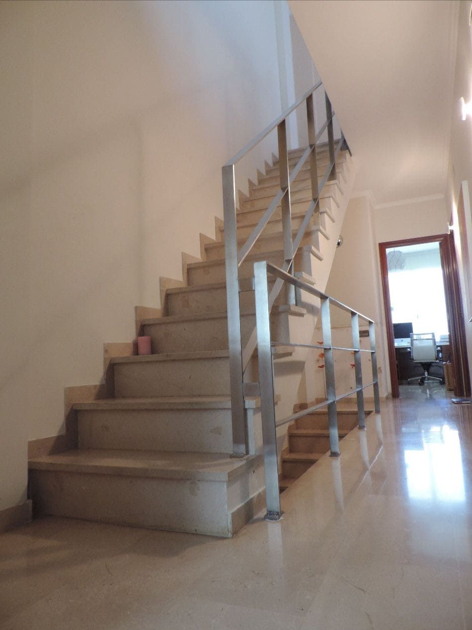 Una escalera con barandilla de acero inoxidable en un pasillo.