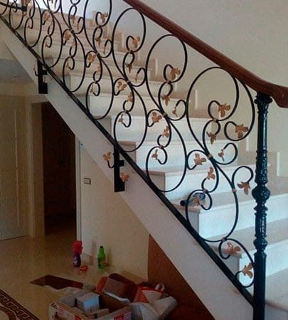 Una escalera con barandilla de hierro forjado y pasamanos de madera